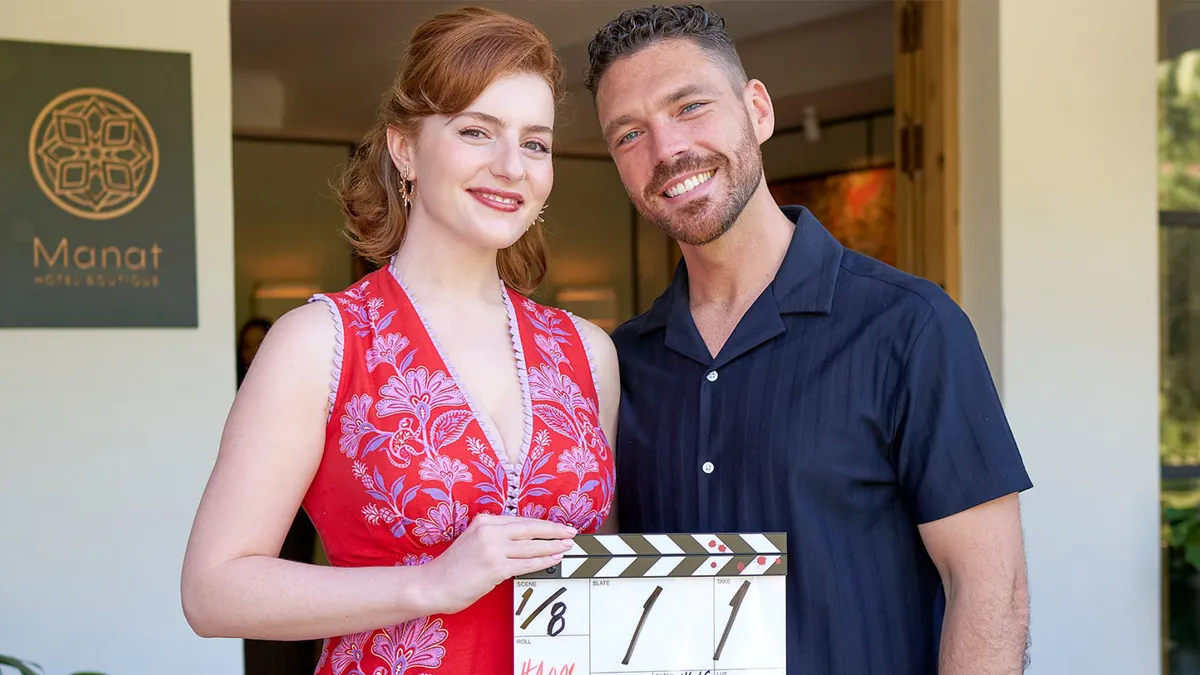 Hannah Onslow and James Nelson-Joyce on set holding a clapperboard