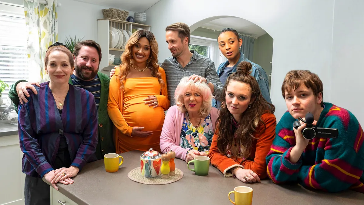 Here We Go cast pose for a photo around a kitchen table