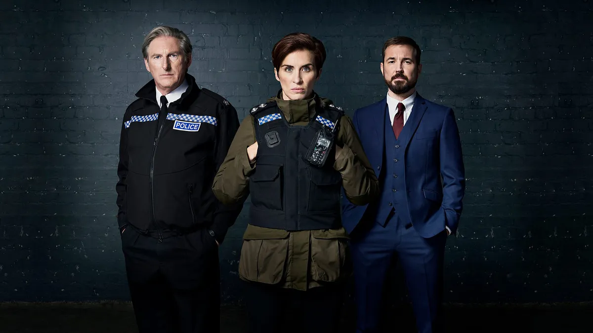Three people - one woman and two men - stand together. One wears police uniform, a second wears a police vest over plain clothes and the third stands in a blue suit looking serious